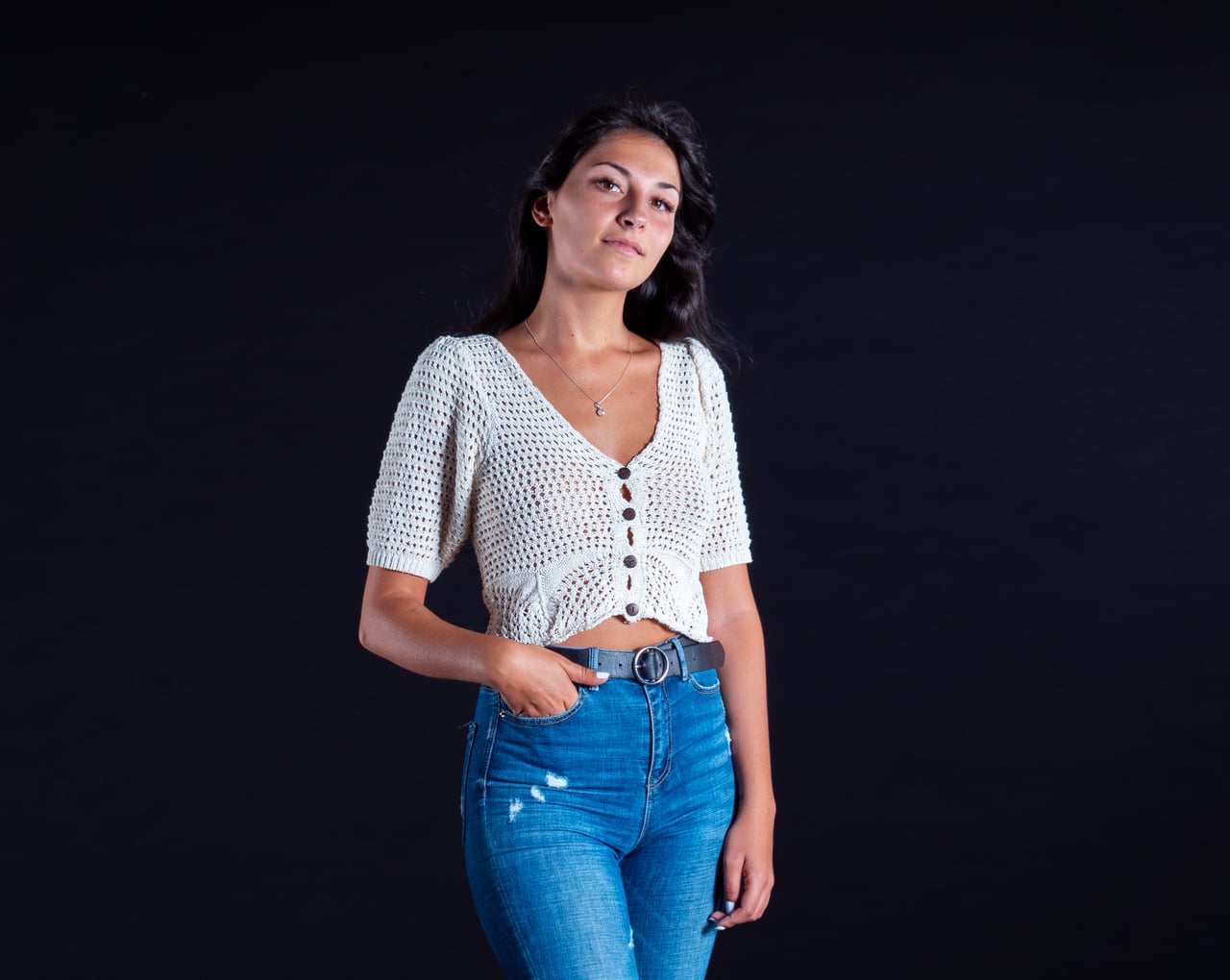 Dona jove amb vestit floral en estudi negre, postura dinàmica amb cabell en moviment.