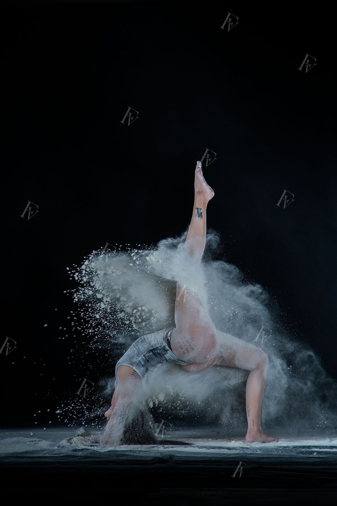 Ballarina amb leotard en pose amb farina blanca caient en estudi fons negre.