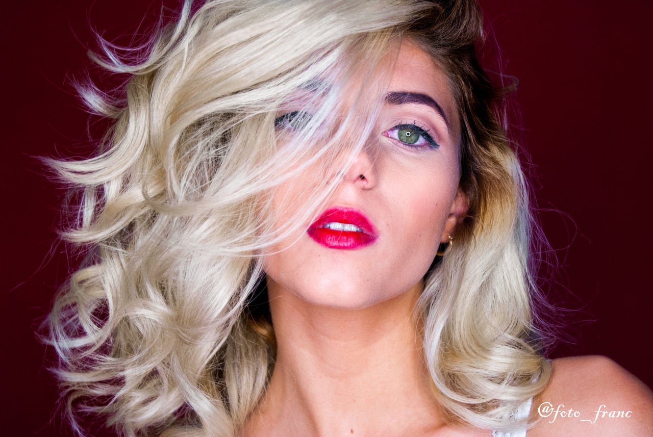 Dona rossa amb llenceria bordeus en pose editorial cos sencer, fons càlid rústic.