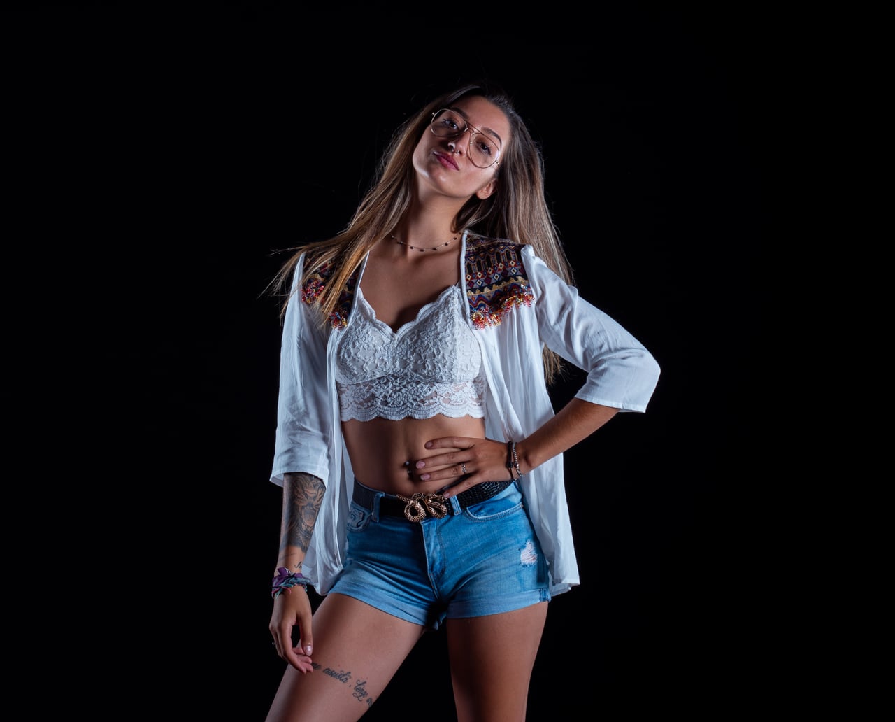 Dona rossa amb look streetwear ètnic en pose editorial, fons d'estudi negre low-key.